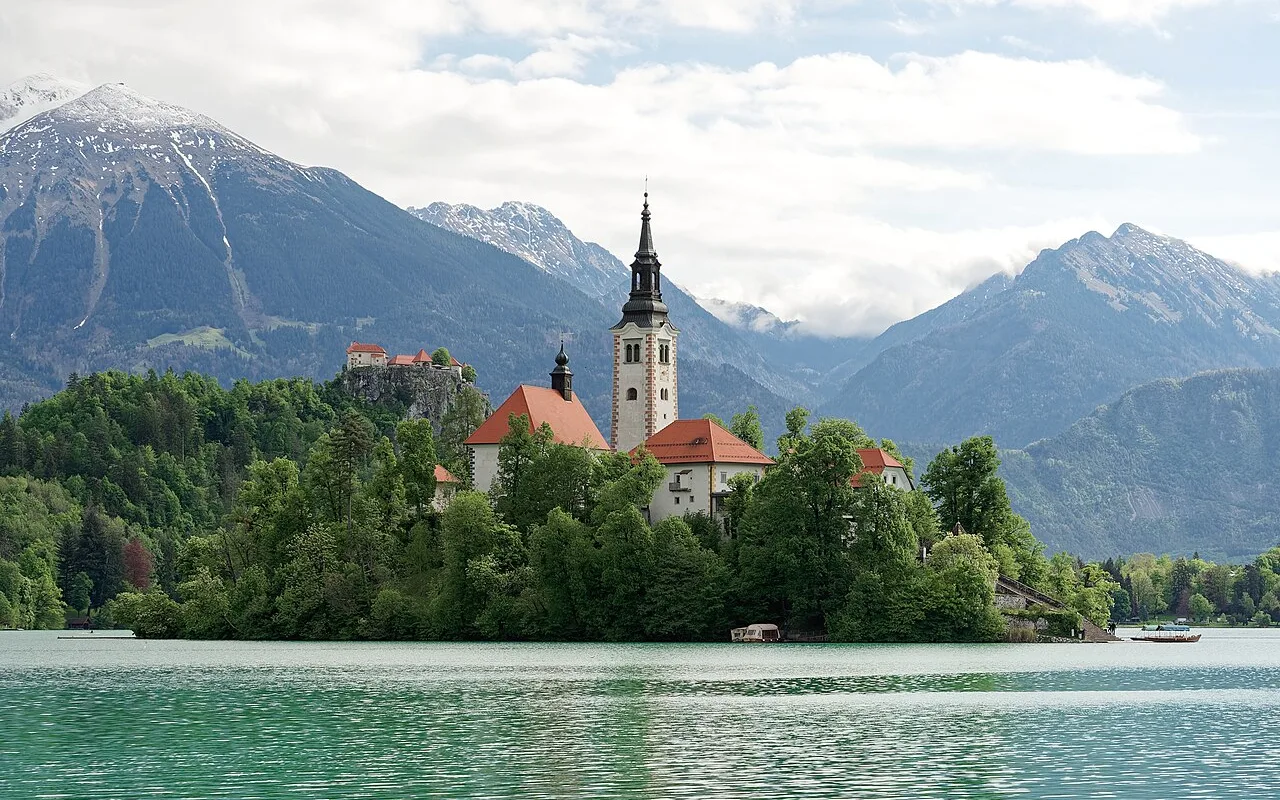 The pilgrimage church on Bled Island seen across the water with mountains behind